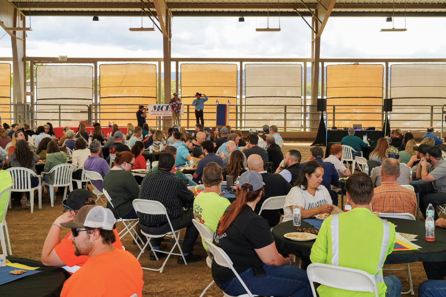 Mesa County employees have lunch in a large covered arena at the county fairgrounds. Photo shows dozens of people sitting at tables and chairs in a large, open-air structure.